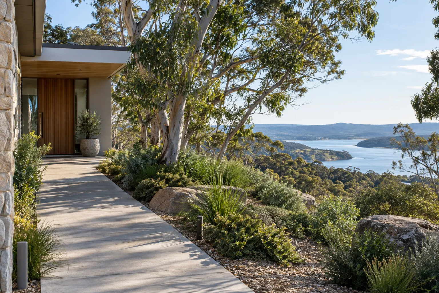 Concrete entry path at a coastal NSW home with eucalyptus and distant water