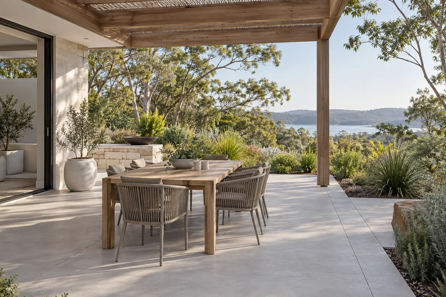 Concrete outdoor dining patio beneath a timber pergola